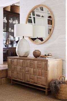 a white vase sitting on top of a wooden dresser next to a lamp and mirror