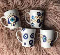 three coffee mugs with blue eyes on them sitting on a furnishing area