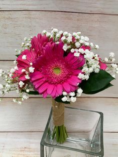 a pink and white flower arrangement in a glass vase