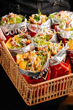 a basket filled with lots of taco salads and condiments on top of each other