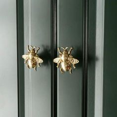 two gold bees are hanging on the side of a green door