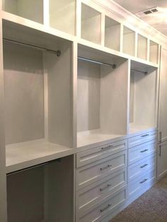 an empty walk - in closet with white cabinets and drawers on the wall, along with carpeted flooring