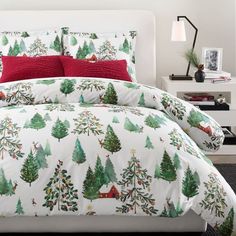 a bed with christmas trees on it and red pillows