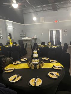 a room filled with black tables and yellow tablecloths on top of each table