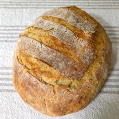 a round loaf of bread sitting on top of a white and gray striped towel next to a knife