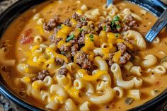 a close up of a bowl of soup with noodles and cheese on top, ready to be eaten