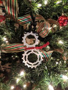 a christmas ornament hanging from the top of a tree with ribbon around it