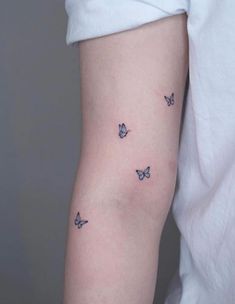 a woman's arm with three small butterflies on the left side of her arm