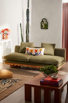 a living room with a couch, table and potted cactus in the corner on the wall