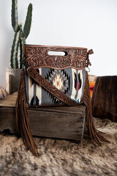 Amazing saddle blanket purse with side fringe detail. Tooled leather top with cradle handle. Zipper top closure. Fully lined inside with side zipper privacy pocket and two open side pockets. All purses come with detachable/optional tooled crossbody strap. Has flat leather bottom for protection and structure. Measures: H13" x W15" x D4" Saddle Blanket Purse, Western Crossbody Purse, Western Bags Purses, Hand Bags Ideas, Western Bags, Purse With Fringe, Blanket Purse, Western Bag, Vegan Design