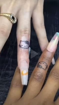 two people with hello kitty tattoos on their fingers