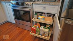 an open refrigerator door in a kitchen next to a stove and oven with food on it