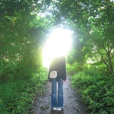 a person standing in the middle of a forest with their back turned towards the camera