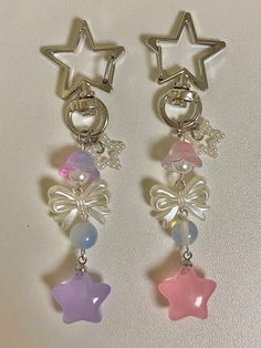 two star shaped earrings with charms attached to them