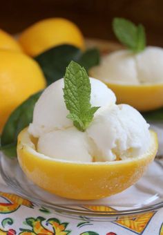 two lemon halves with ice cream in them on a plate next to some lemons