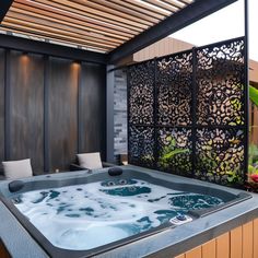 an outdoor hot tub in the middle of a patio with wood slatted walls