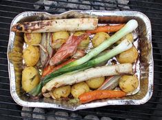 there are many vegetables on the grill and some meats in it, as well as potatoes