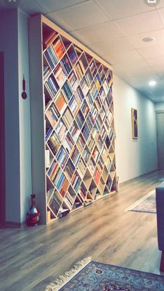 a living room filled with furniture and a large book shelf on the wall behind it