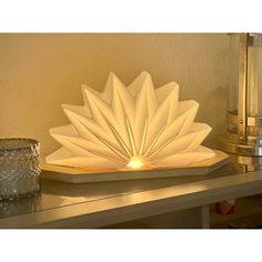 a white lamp sitting on top of a table next to a glass vase and candle