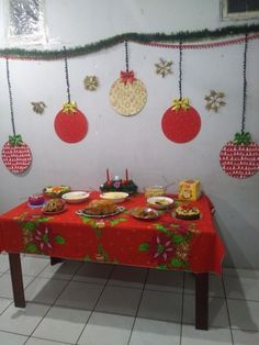 a red table topped with lots of food next to a wall covered in christmas decorations