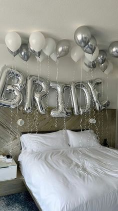 a bedroom decorated with balloons and the word bride spelled out in silver letters on the wall