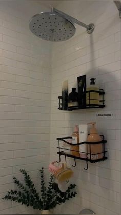 a bathroom with white tiles and black shelves on the wall, along with a shower head