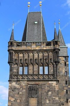 an old building with a clock on the front and side of it, against a blue sky