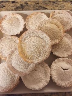 powdered sugar covered donuts in a box on a counter top, ready to be eaten