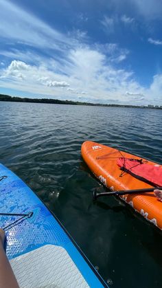 two people in kayaks paddling on the water under a blue sky with wispy clouds