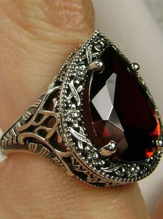 Red Garnet CZ Gemstone Teardrop RingTear Vic Design#D28 Inspired by Victorian and Art Deco designs, this high-quality filigree ring is handcrafted in sterling silver. This teardrop ring is set with an 8 carat pear cut flawless red CZ (Cubic Zirconia) gemstone. The gem is 16mm (~5/8") x 12mm (~1/2"). The gorgeous stone has a lovely vibrant color. The inside of the band is marked 925 for sterling silver. Notice the beautiful filigree of the silver setting. This is a ring with beauty and grace. The Ornate Red Teardrop Jewelry, Filigree Drop Jewelry For Anniversary, Classic Teardrop Jewelry With Intricate Design, Classic Red Teardrop Ring, Teardrop Garnet Jewelry For Anniversary, Elegant Pear-shaped Garnet Jewelry, Gold Jewlry, Ring Teardrop, Victorian Filigree