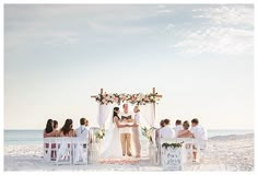 a couple getting married on the beach with their wedding party in white and pink colors