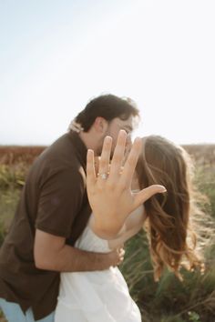 a man and woman kissing while holding their hands up in the air with one hand