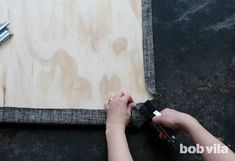 a person is working with wood on the floor and using scissors to cut it into pieces