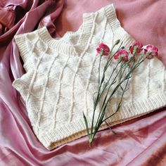 a sweater and flowers are laying on a bed