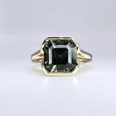 a green tourmaline ring sitting on top of a white surface