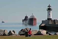 two ships in the water near rocks and a lighthouse