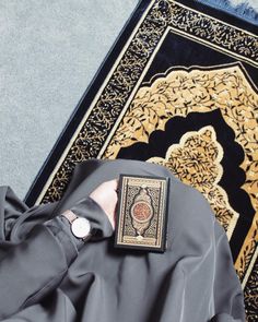 a person wearing a gray outfit standing in front of a rug with an intricate design on it