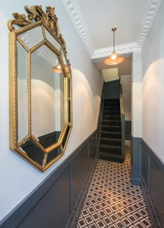 the hallway is decorated in gold and black with an ornate mirror hanging on the wall