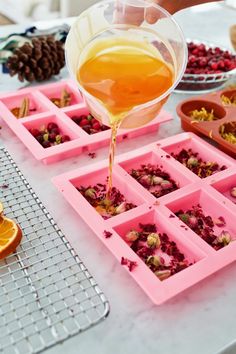 someone pours orange juice into small trays on a table with other food items