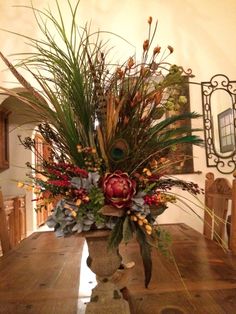 a vase filled with lots of flowers on top of a wooden table in a room