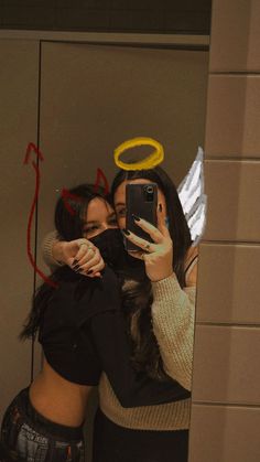 two women taking a selfie in front of a mirror with their arms around each other