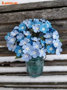 blue flowers in a vase sitting on a bench