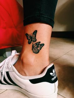 a woman's foot with a butterfly tattoo on her left ankle and the bottom part of her shoe