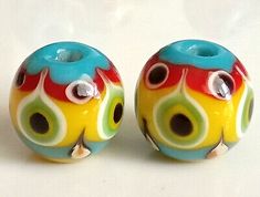 two colorful glass beads with holes in the middle on a white surface, each bead has one hole at the center