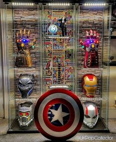 a display case filled with different types of avengers masks and lights on brick wall behind it