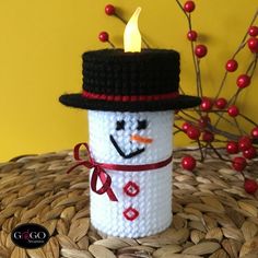 a crocheted snowman candle holder sitting on top of a wicker basket