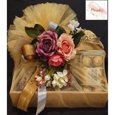 a gift box with flowers and chocolates wrapped in organe, on a black background