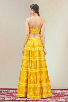 Mustard lehenga highlighted with mirror-thread embroidery and drawstring with tassels at the waist. Comes with corset-style blouse and dupatta.
Components:3
Embroidered
Neckline: V-Neck
Sleeve Length:Sleeveless
Fabric:Dupion Silk
Color:Yellow
Embroidered blouse
Beaded tassels at the hem
Closure: 
Blouse: Hooks at the back
Lehenga: Drawstring with tassels at the waist
Note: The fabric is silk blend and not pure silk - Aza Fashions Sleeveless Yellow Lehenga With Resham Embroidery, Sleeveless Lehenga For Reception With Dori Work, Sleeveless Sets With Dori Work For Navratri, Traditional Lehenga With Gota Work, Traditional Sleeveless Lehenga With Gota Work, Sleeveless Gota Work Lehenga For Navratri, Anarkali Style Lehenga With Dori Work, Traditional Sleeveless Choli With Gota Work, Sleeveless Lehenga With Dori Work