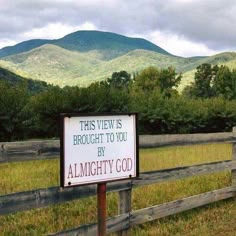 a sign in front of a fence that says, this view is brought to you by al mighty god