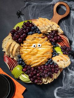 a plate with grapes, apples and crackers in the shape of a face on it